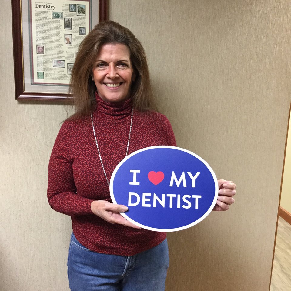 female patient holding up sign for dentist