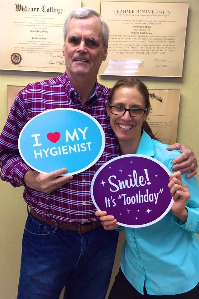 Male patient holding up sign with hygienist