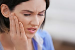 woman holding cheek from jaw pain